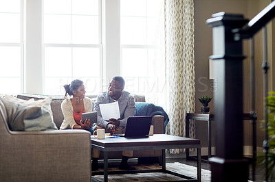 Buy stock photo Shot of a young couple going through paperwork together on the sofa at home