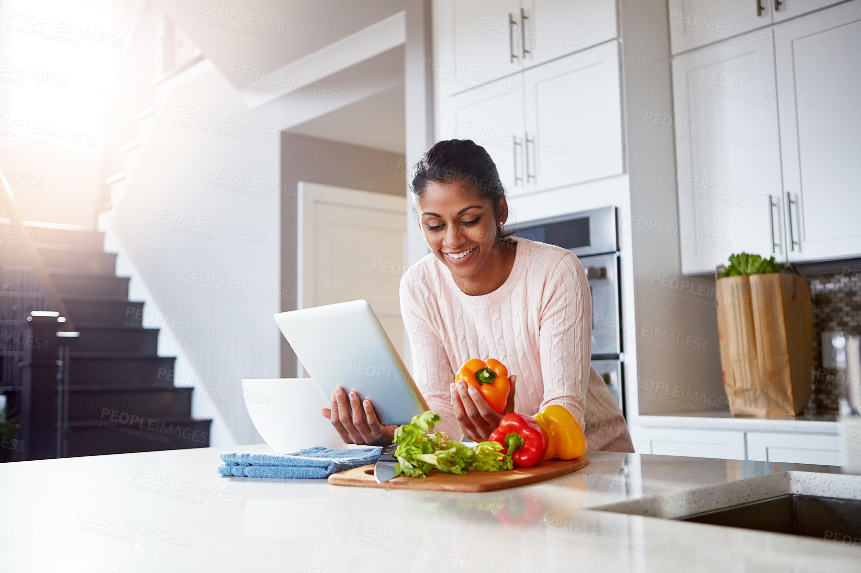 Buy stock photo Shot of a young woman using a digital tablet while preparing a healthy meal at home