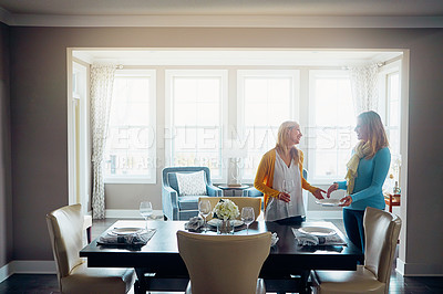 Buy stock photo Shot of two women setting up the dining room table