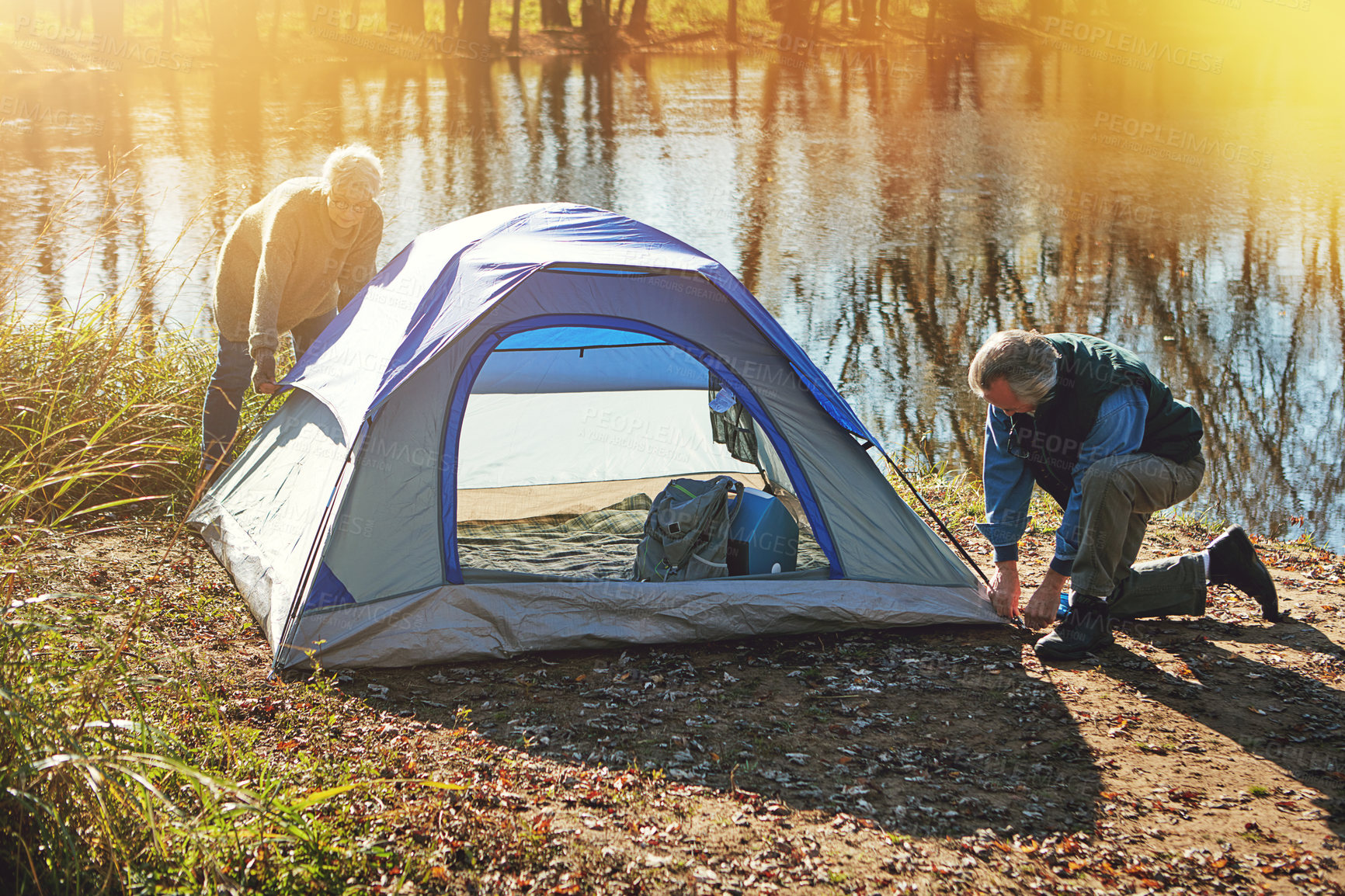 Buy stock photo Shot of a senior couple setting up a tent while camping in the wilderness