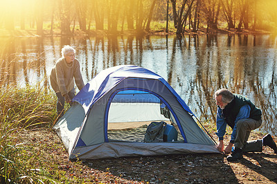 Buy stock photo Shot of a senior couple setting up a tent while camping in the wilderness