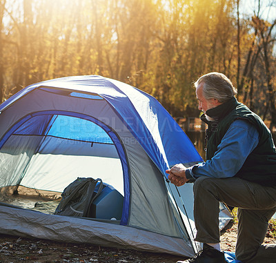 Buy stock photo Shot of a senior man setting up a tent while camping in the wilderness