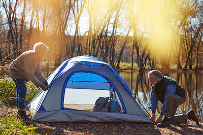 Buy stock photo Shot of a senior couple setting up a tent while camping in the wilderness