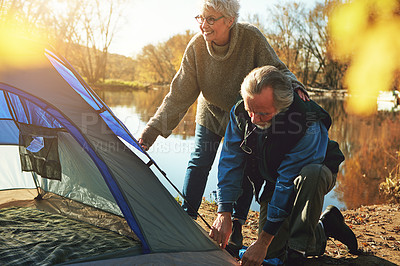 Buy stock photo Shot of a senior couple setting up a tent while camping in the wilderness