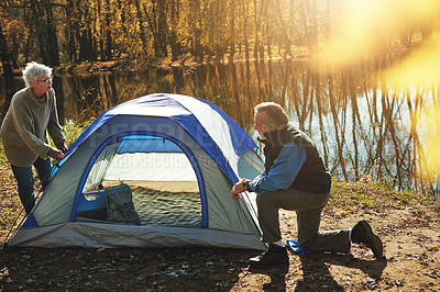 Buy stock photo Shot of a senior couple setting up a tent while camping in the wilderness