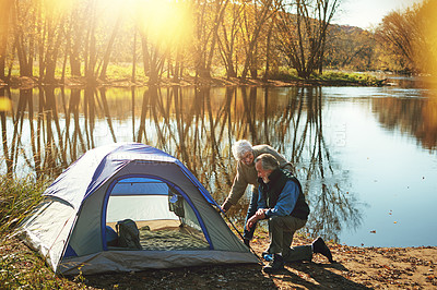 Buy stock photo Shot of a senior couple setting up a tent while camping in the wilderness