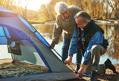 Buy stock photo Shot of a senior couple setting up a tent while camping in the wilderness