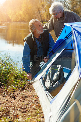 Buy stock photo Shot of a senior couple setting up a tent while camping in the wilderness