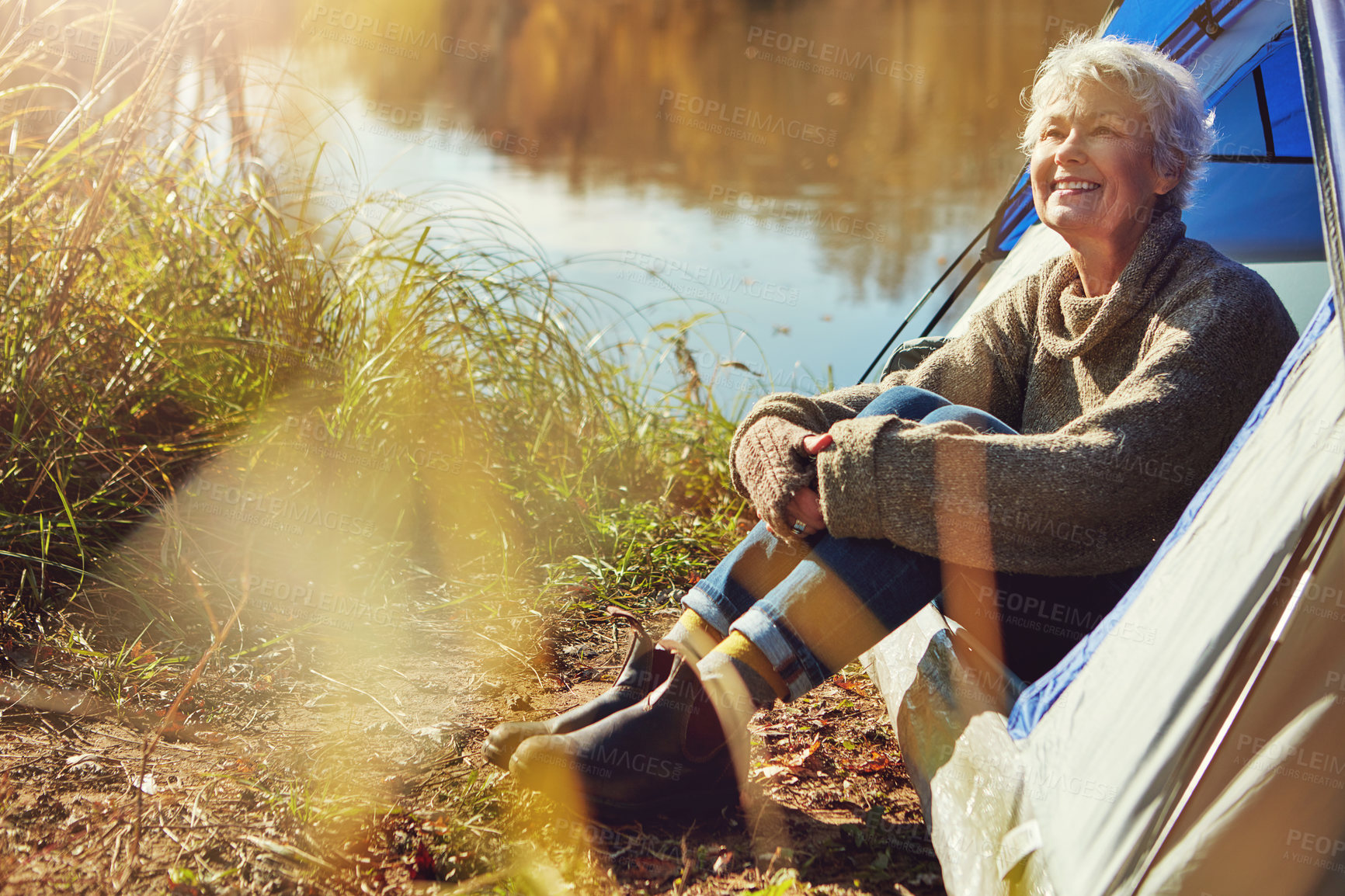 Buy stock photo Camp, mature woman and nature in tent, smile and outdoor to enjoy fresh air, freedom and sunshine. Retirement, hobby and morning at campsite, happy and healthy with wellness and relaxing natural view