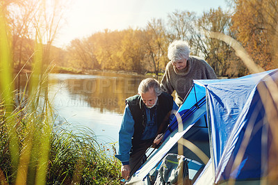 Buy stock photo Shot of a senior couple setting up a tent while camping in the wilderness