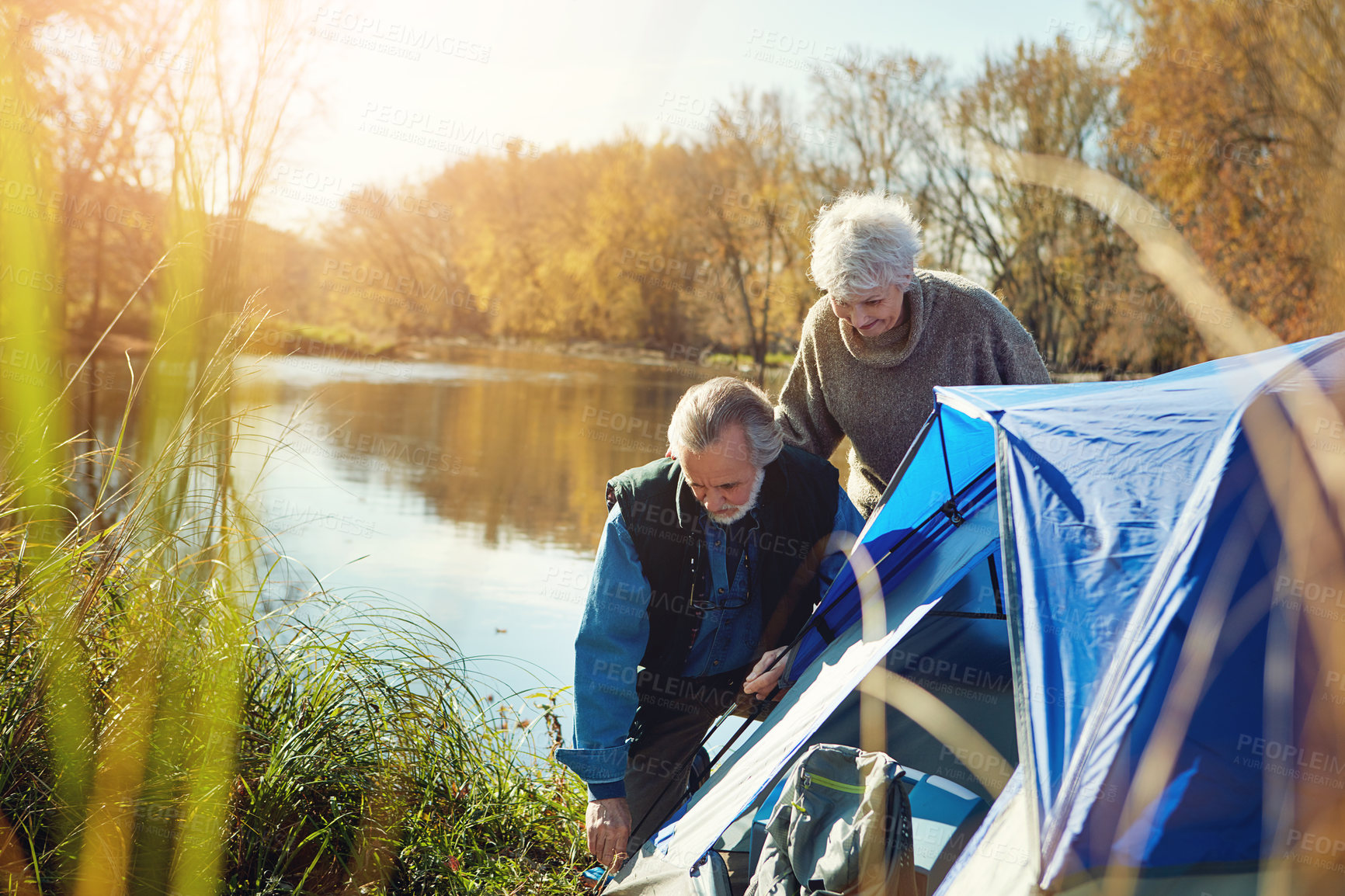 Buy stock photo Shot of a senior couple setting up a tent while camping in the wilderness