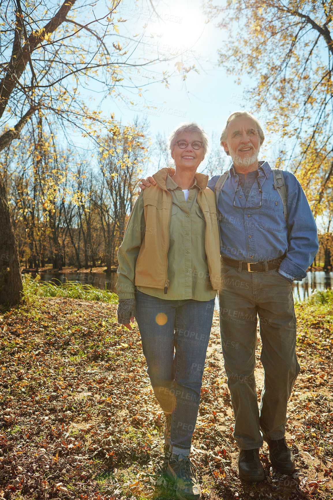 Buy stock photo Love, nature and senior couple in forest with backpack for walk, exercise and bonding together. Smile, travel and elderly man and woman in retirement enjoying view by woods in Autumn in England