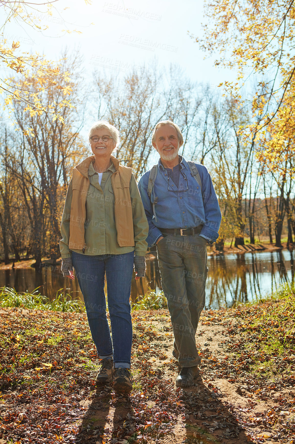 Buy stock photo Smile, nature and senior couple in forest with backpack for walk, exercise and bonding together. Happy, love and elderly man and woman in retirement enjoying view by woods in Autumn in England.