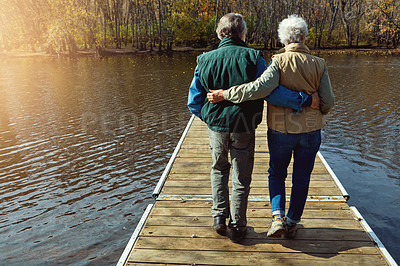 Buy stock photo Rearview shot of a senior couple standing on a pier next to a lake