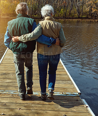 Buy stock photo Rearview shot of a senior couple standing on a pier next to a lake