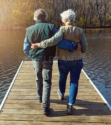 Buy stock photo Rearview shot of a senior couple standing on a pier next to a lake