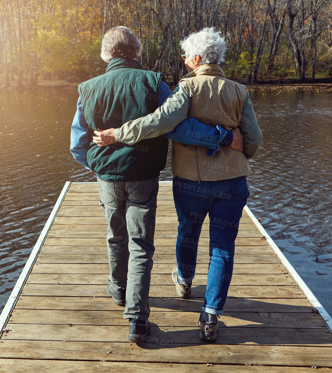 Buy stock photo Rearview shot of a senior couple standing on a pier next to a lake