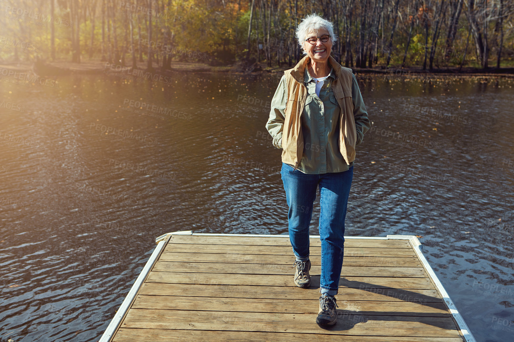 Buy stock photo Shot of a senior woman going for a walk on a jetty next to a lake