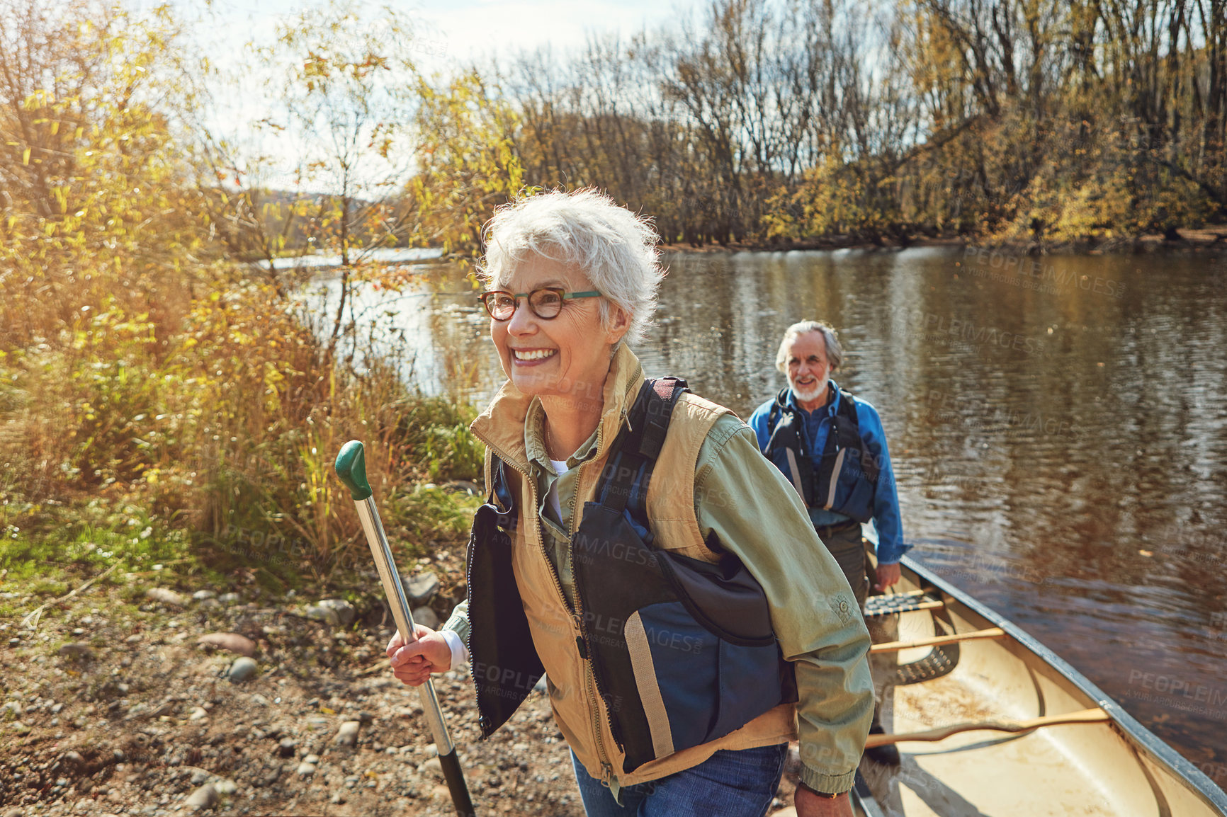 Buy stock photo Senior woman, happy and canoe at lake for adventure, bonding and couple with hiking in countryside. Elderly people, smile and boat for vacation, relationship and outdoor by river for nature tourism