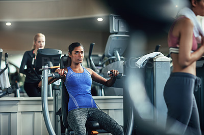 Buy stock photo Shot of a young woman working out with a chest press at a gym