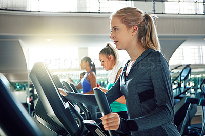 Buy stock photo Shot of a young woman working out with a machine at a gym