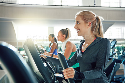 Buy stock photo Shot of a young woman working out with a machine at a gym