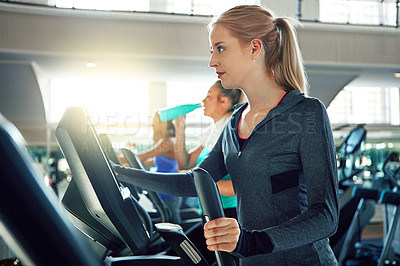 Buy stock photo Shot of a young woman working out with a machine at a gym