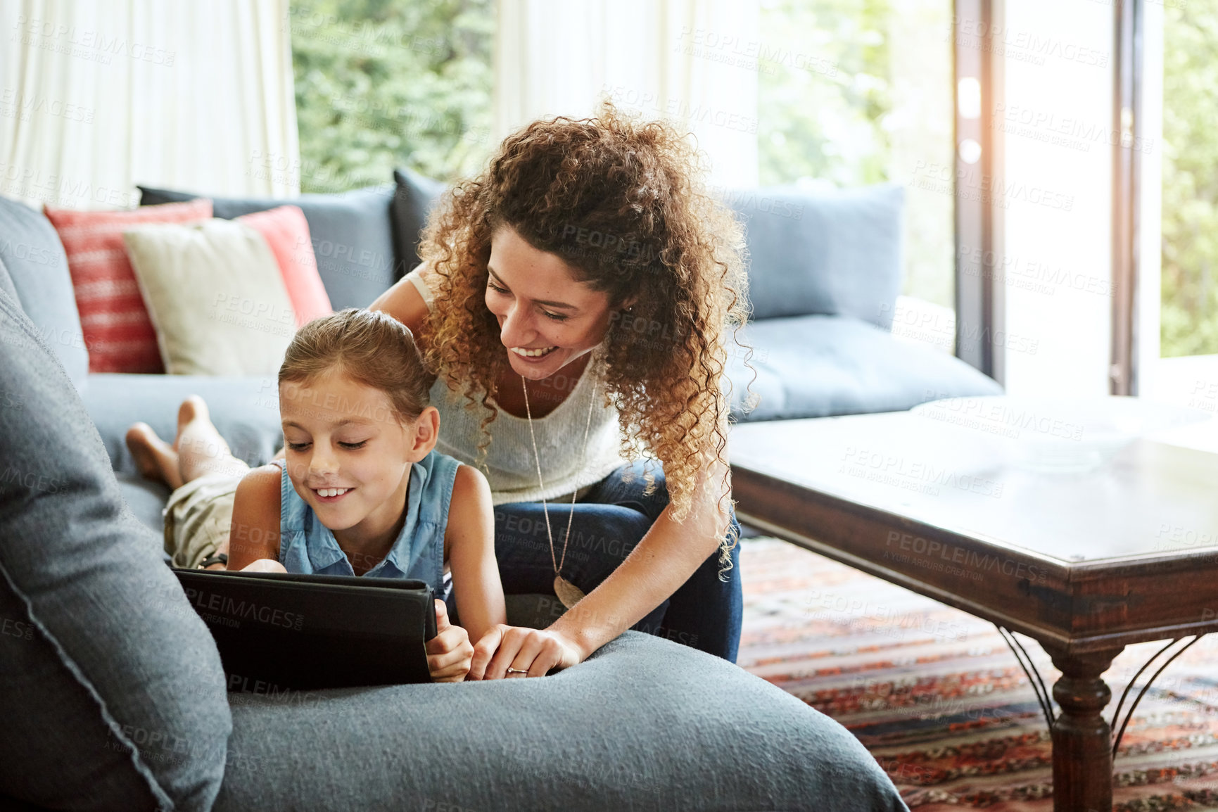 Buy stock photo Shot of a mother and her little daughter using a digital tablet together at home