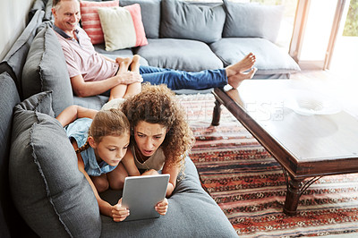 Buy stock photo Shot of a family using a digital tablet while relaxing together at home
