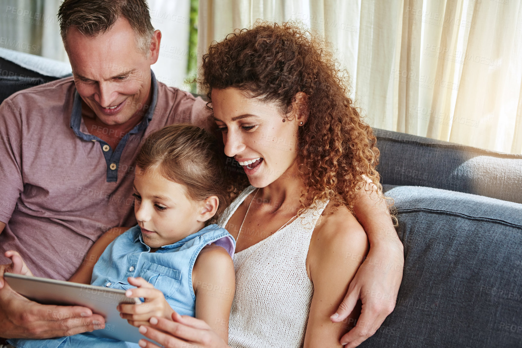 Buy stock photo Shot of a family using a digital tablet while relaxing together at home