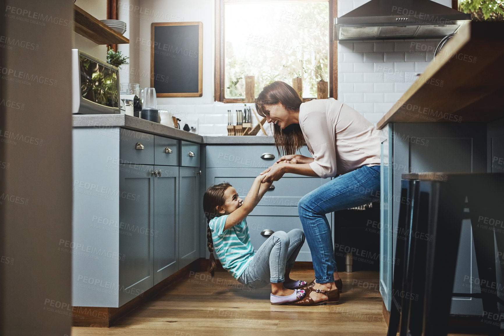 Buy stock photo Shot of a mother playing with her little daughter in the kitchen at home