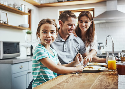 Buy stock photo Portrait of a little girl having breakfast with her parents at home