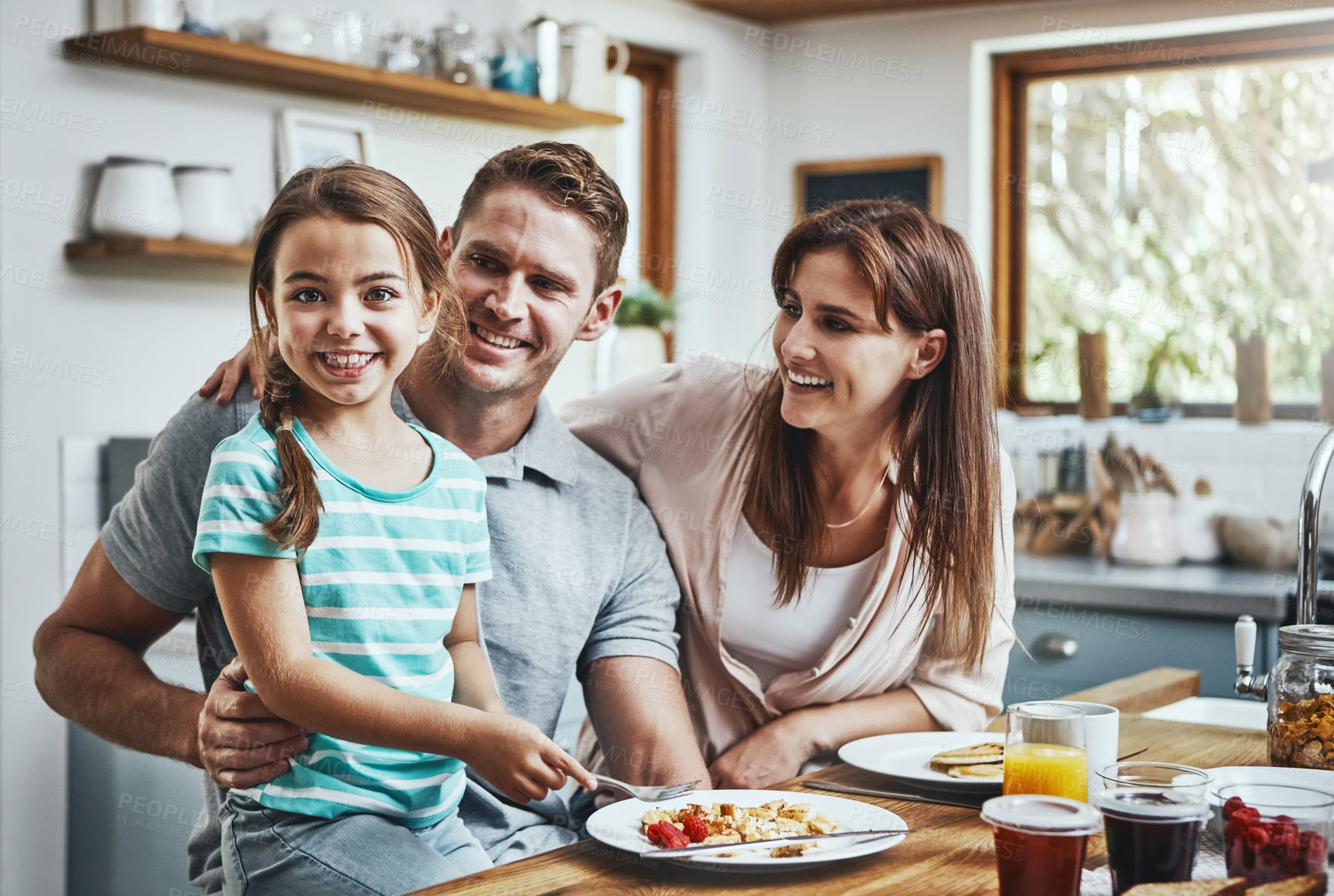 Buy stock photo Portrait of a little girl having breakfast with her parents at home