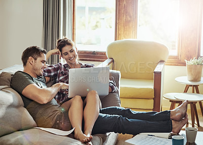 Buy stock photo Shot of a young couple using a laptop and going through paperwork together on the sofa at home