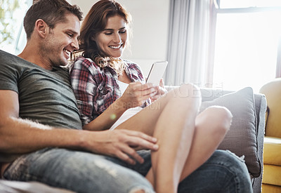 Buy stock photo Shot of a young couple relaxing on the sofa together and using a mobile phone
