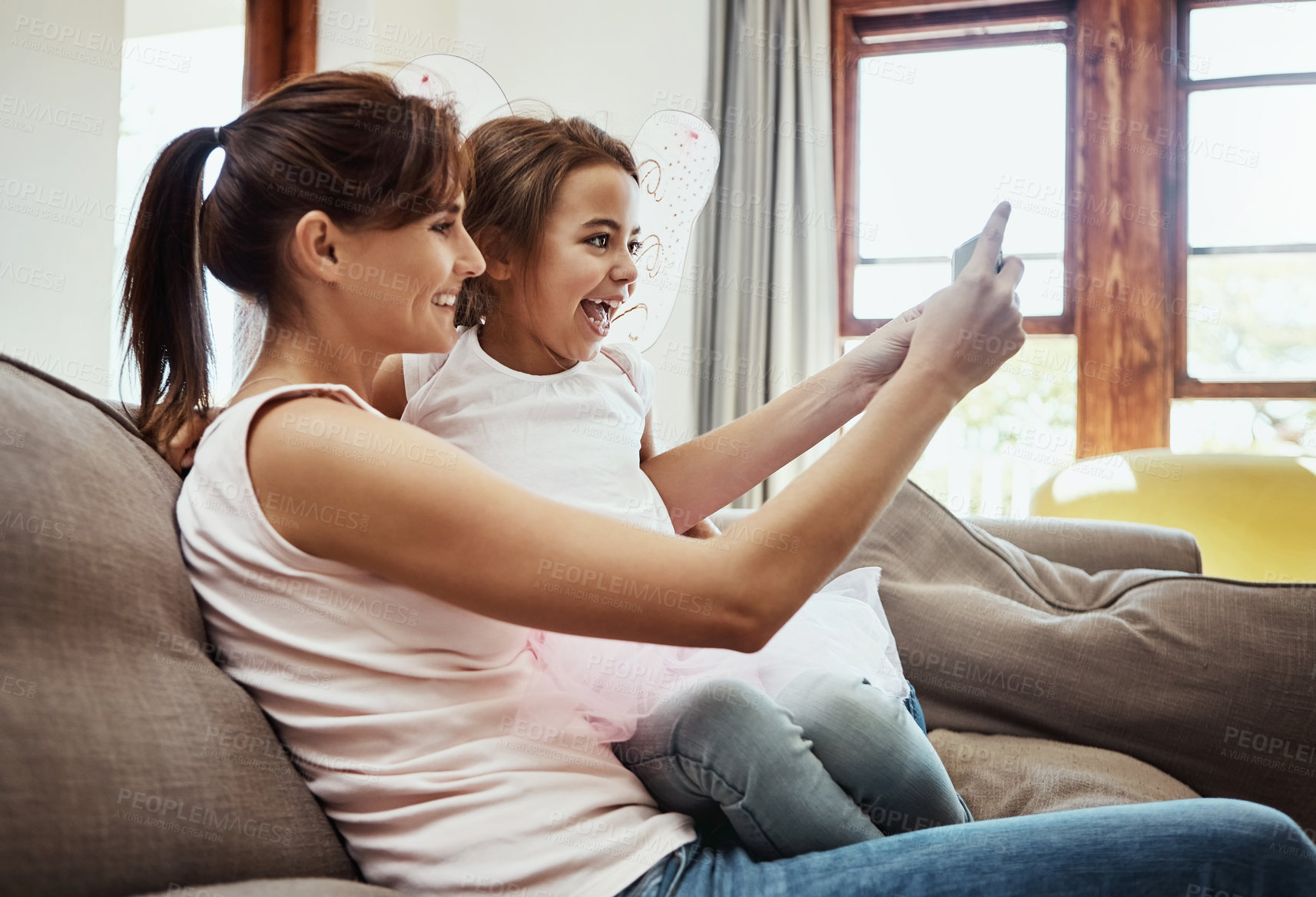 Buy stock photo Mom, girl and selfie on sofa with smile for memories, fun and care with support for child development. family, people and happy in living room on couch for social media, bonding and home to embrace