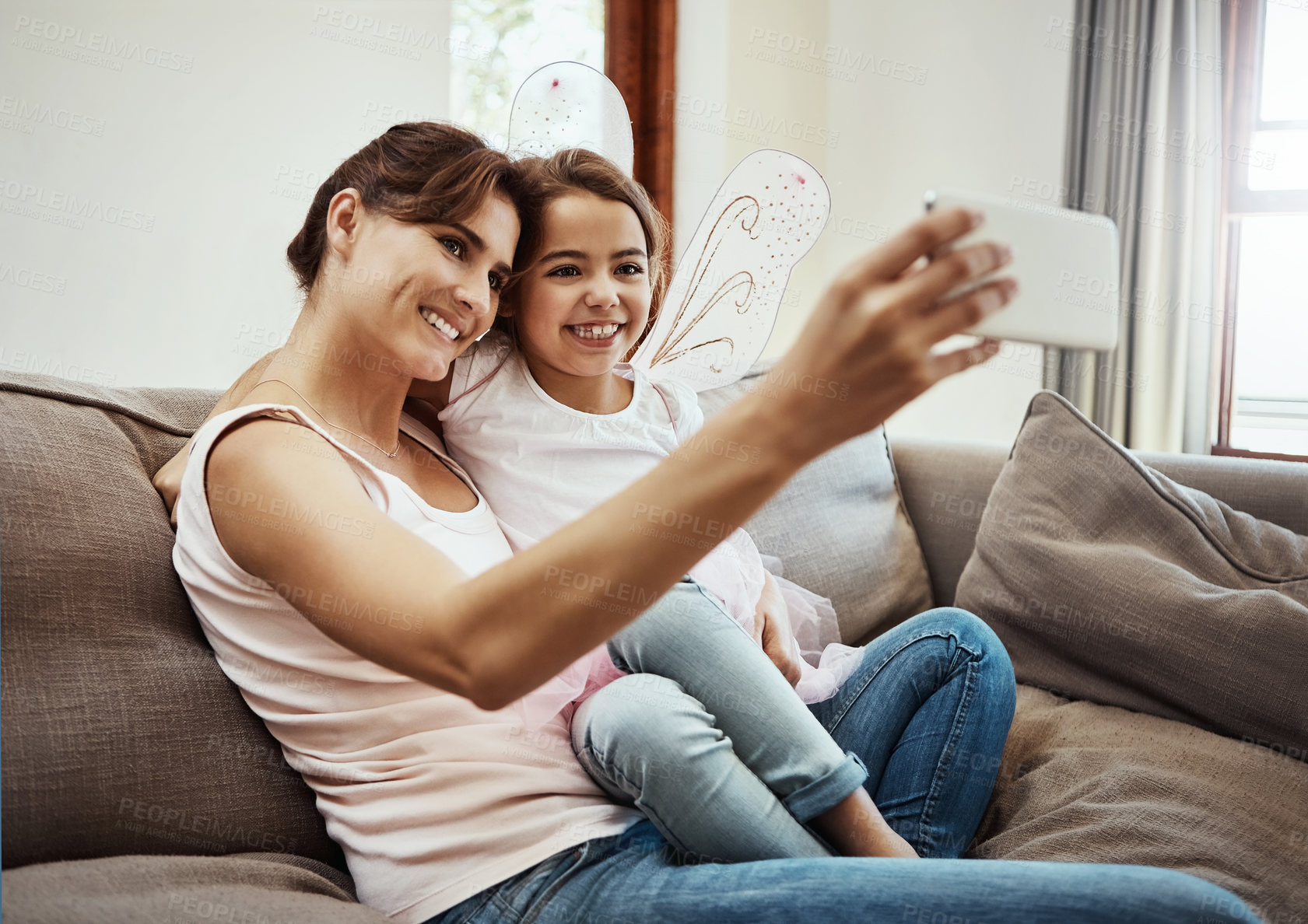 Buy stock photo Mom, girl and happy on selfie on sofa for memories, fun and care with support for child development. Family, people and smile in living room on couch for social media, bonding and home with butterfly