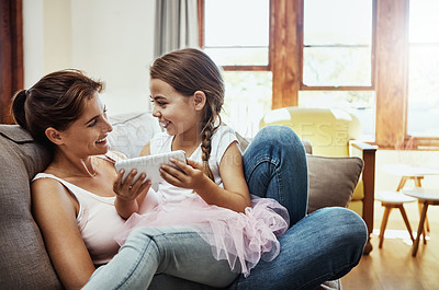 Buy stock photo Shot of a little girl using a cellphone while bonding with her mother at home