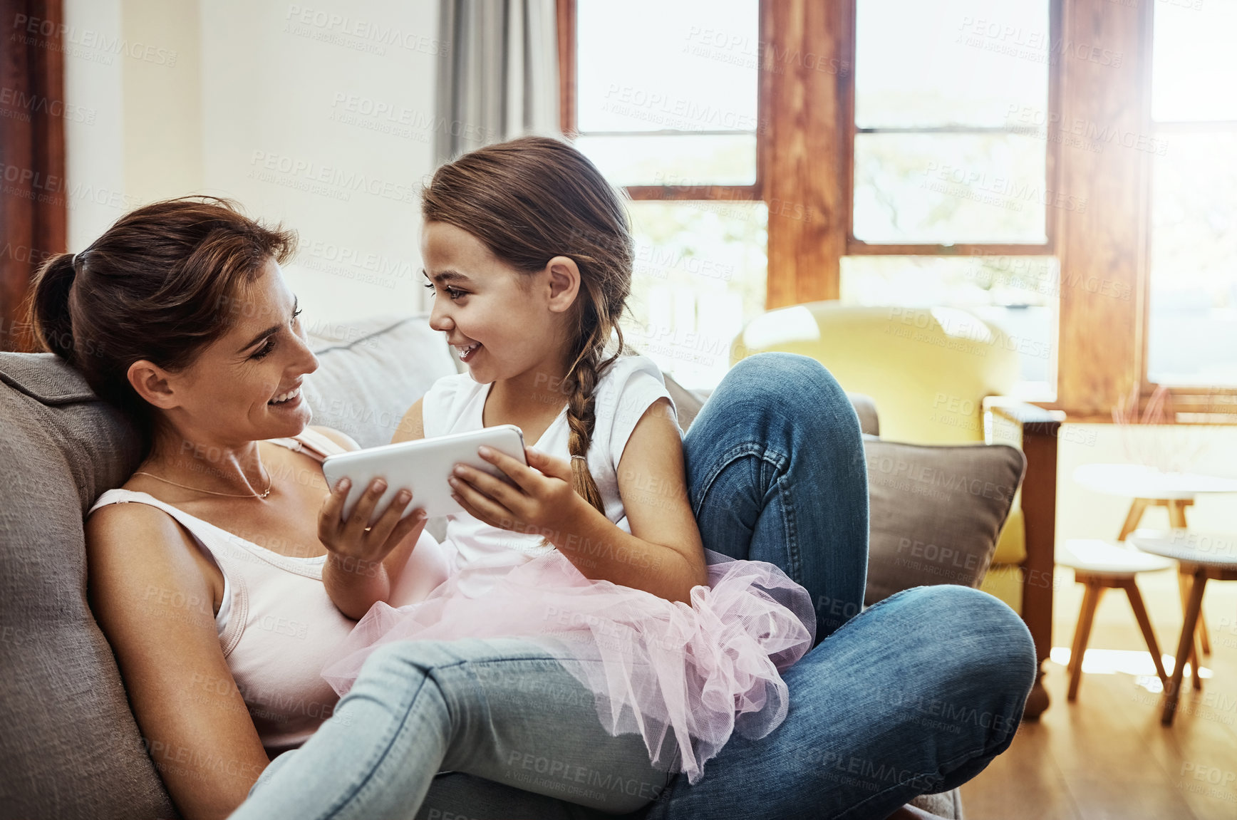 Buy stock photo Shot of a little girl using a cellphone while bonding with her mother at home