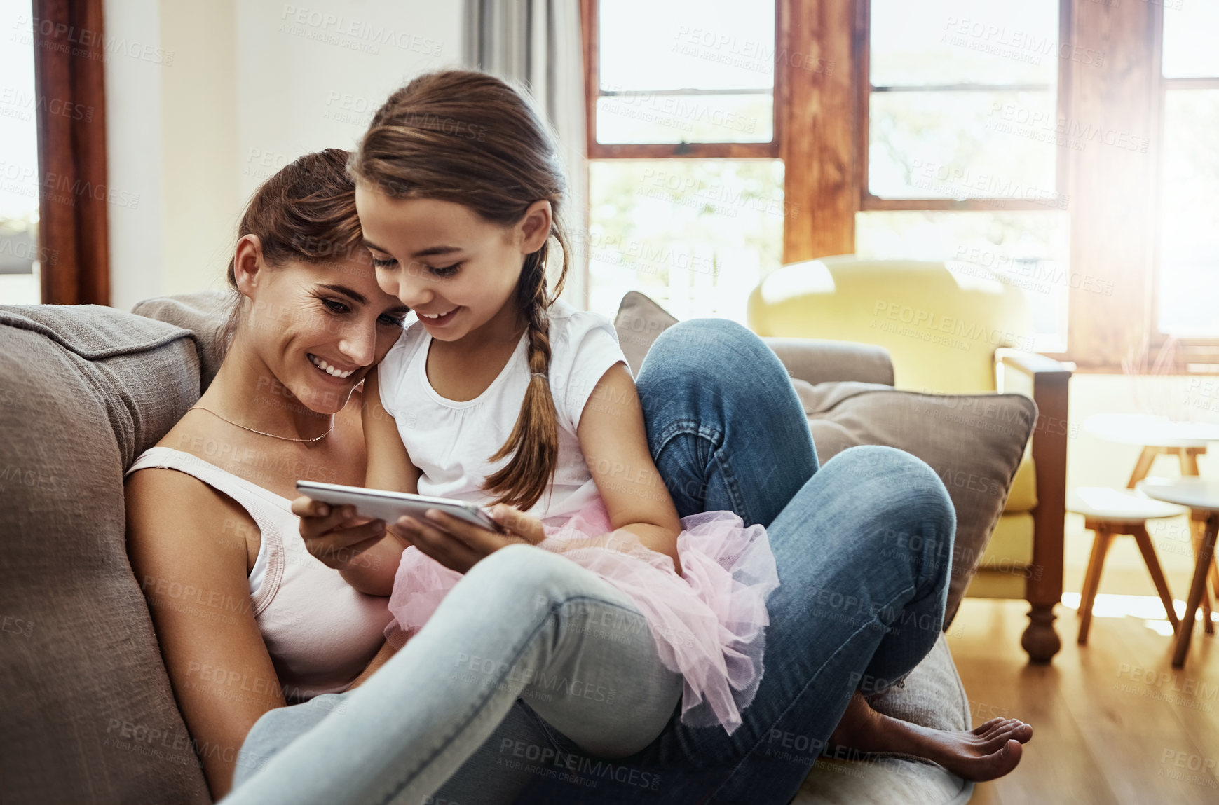 Buy stock photo Shot of a little girl using a cellphone while bonding with her mother at home