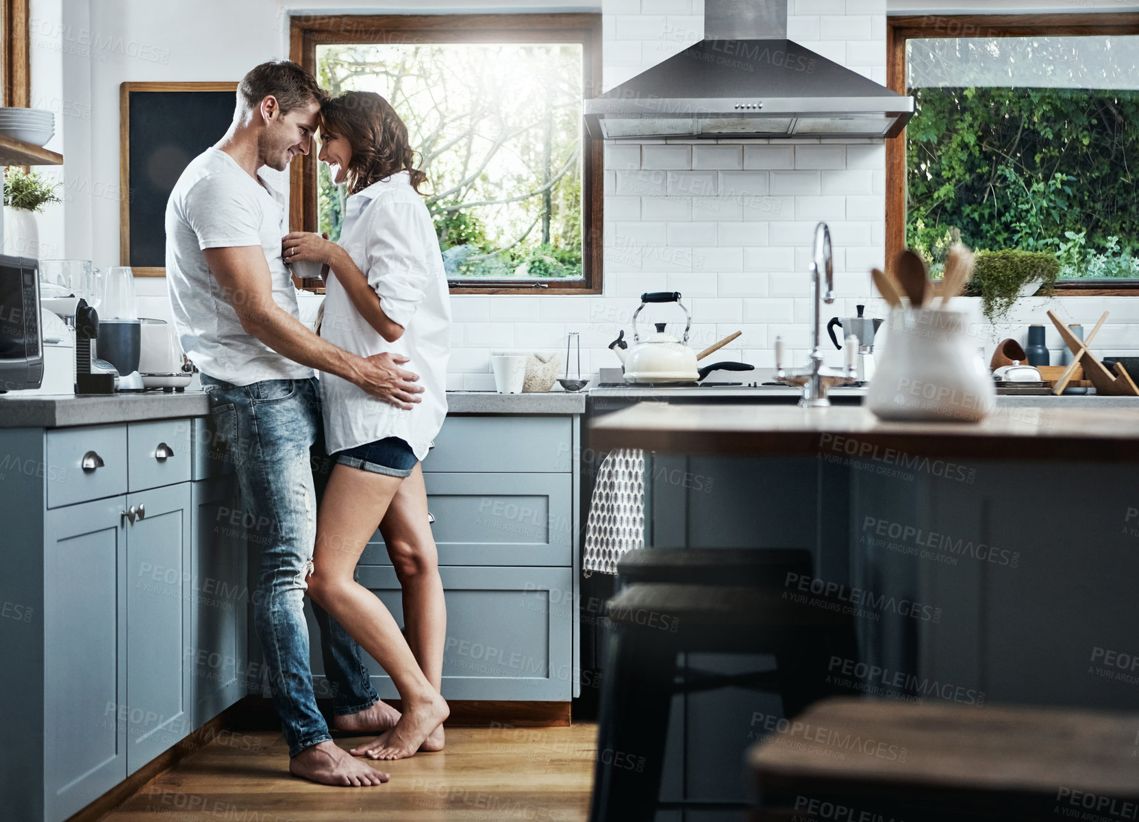 Buy stock photo Shot of an affectionate young couple standing together in the kitchen at home