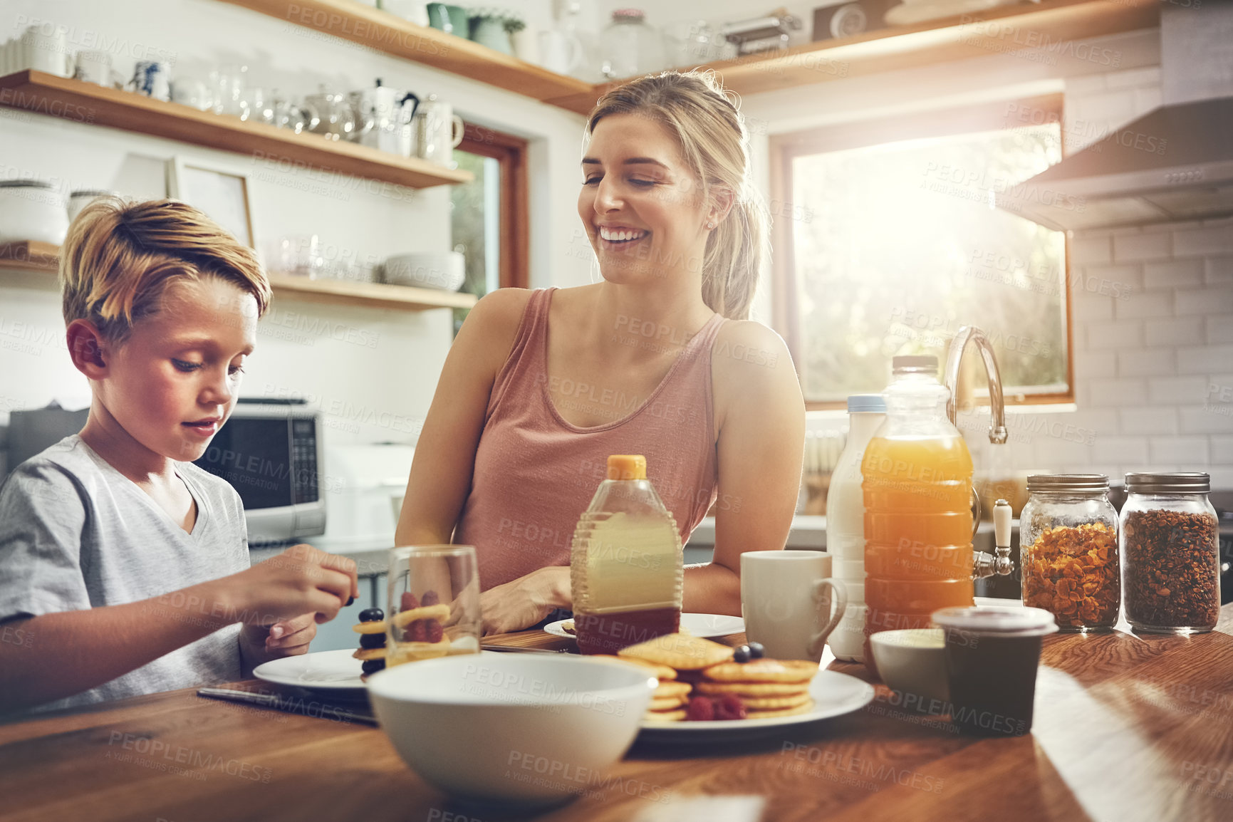 Buy stock photo Shot of a woman sitting with her son while he's having breakfast