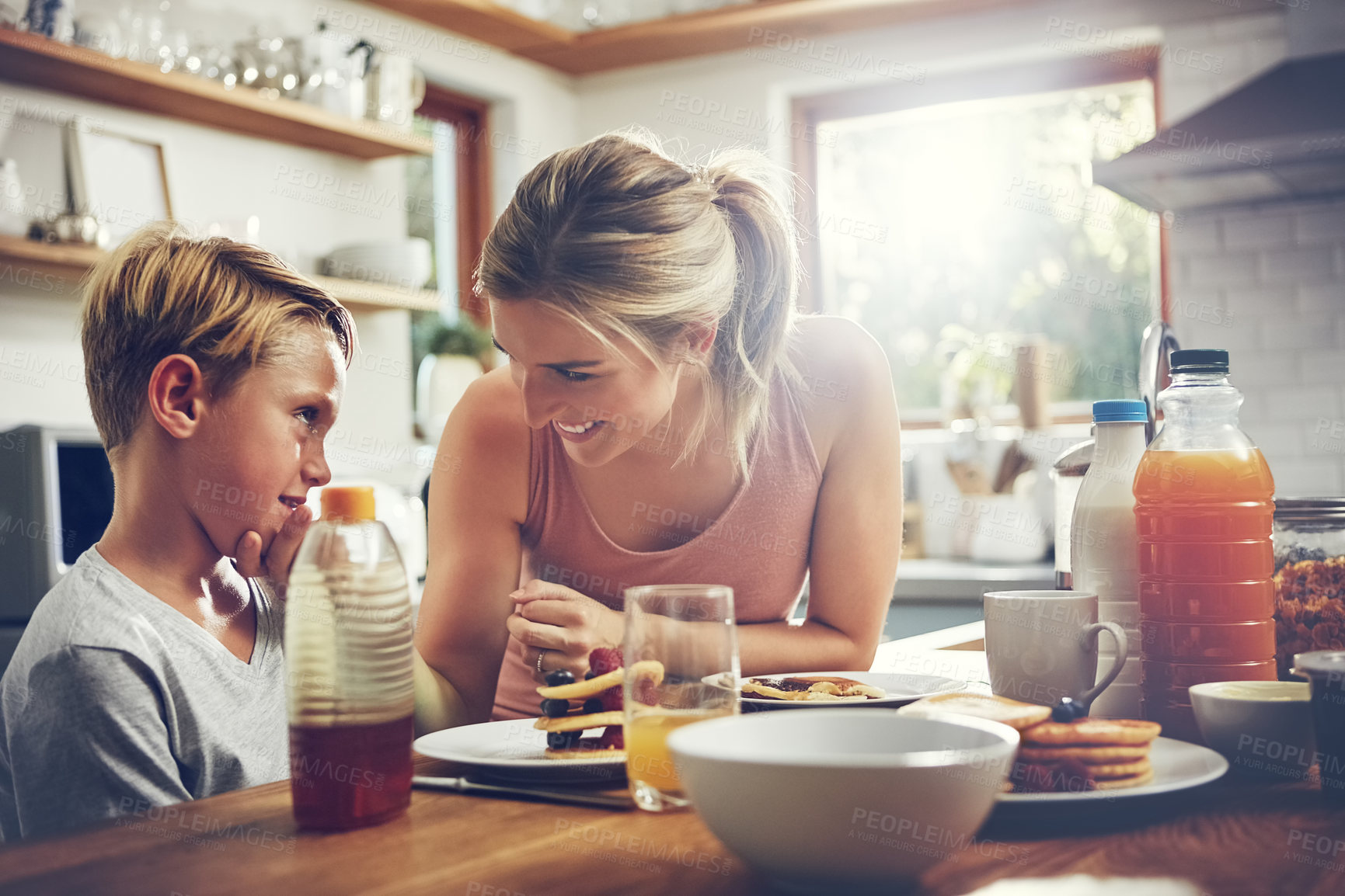 Buy stock photo Shot of a woman sitting with her son while he's having breakfast