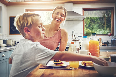 Buy stock photo Shot of a woman sitting with her son while he's having breakfast