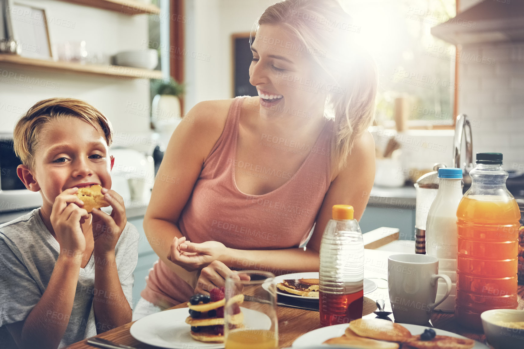 Buy stock photo Shot of a woman sitting with her son while he's having breakfast