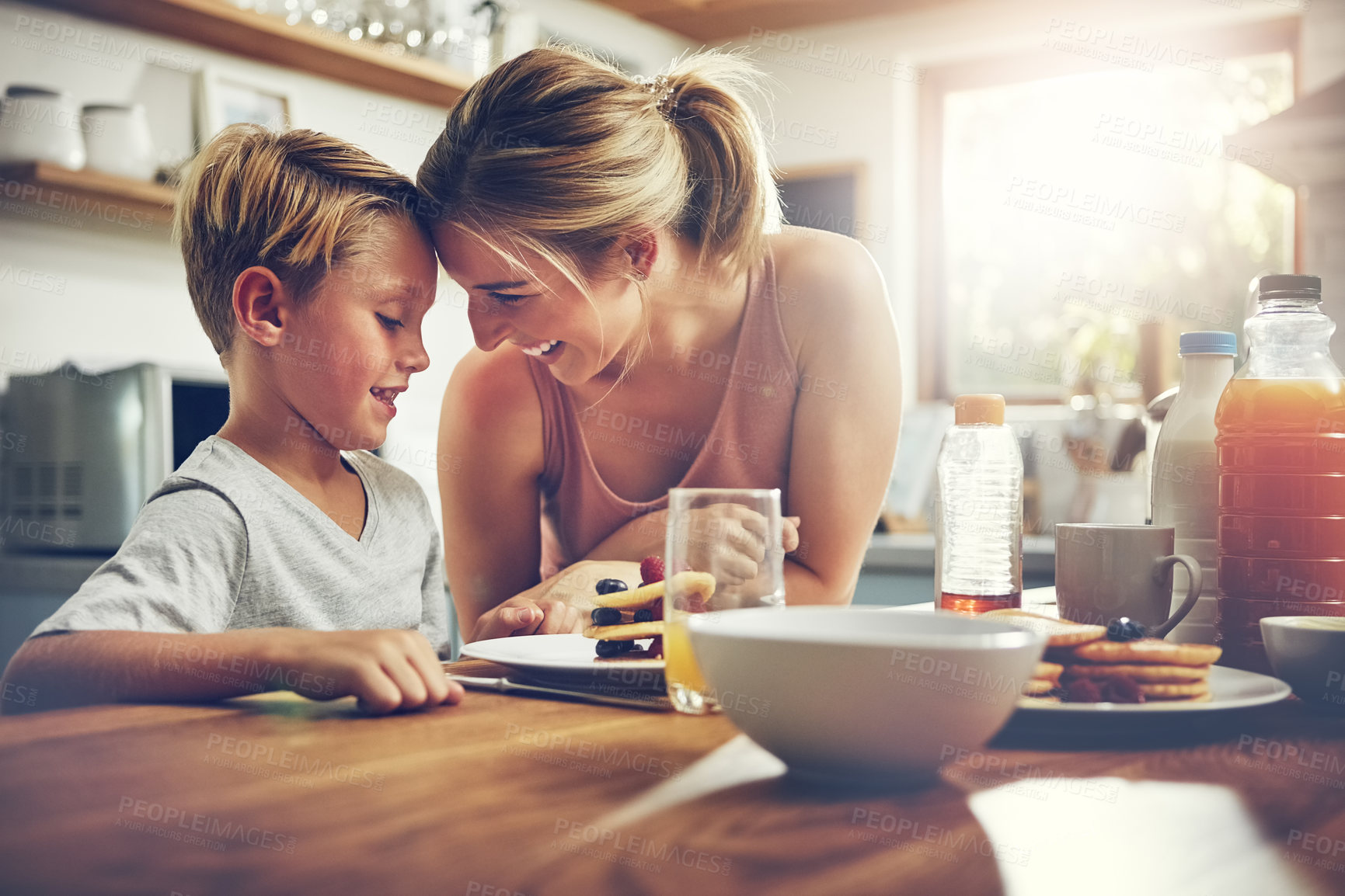 Buy stock photo Shot of a woman sitting with her son while he's having breakfast