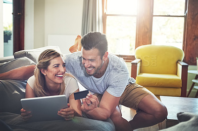 Buy stock photo Shot of a young couple doing some online shopping on a digital tablet
