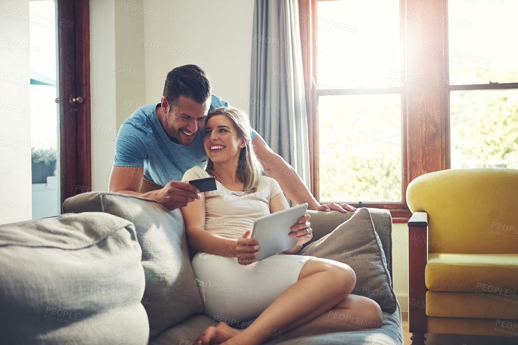 Buy stock photo Shot of a young couple doing some online shopping on a digital tablet