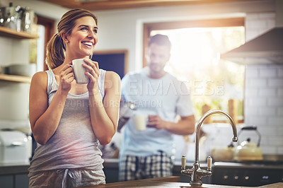 Buy stock photo Shot of a young woman having her morning coffee with her boyfriend standing in the background
