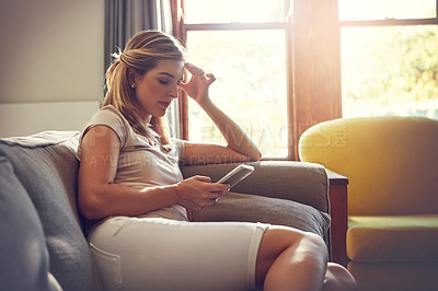 Buy stock photo Shot of a young woman using her digital tablet while relaxing at home